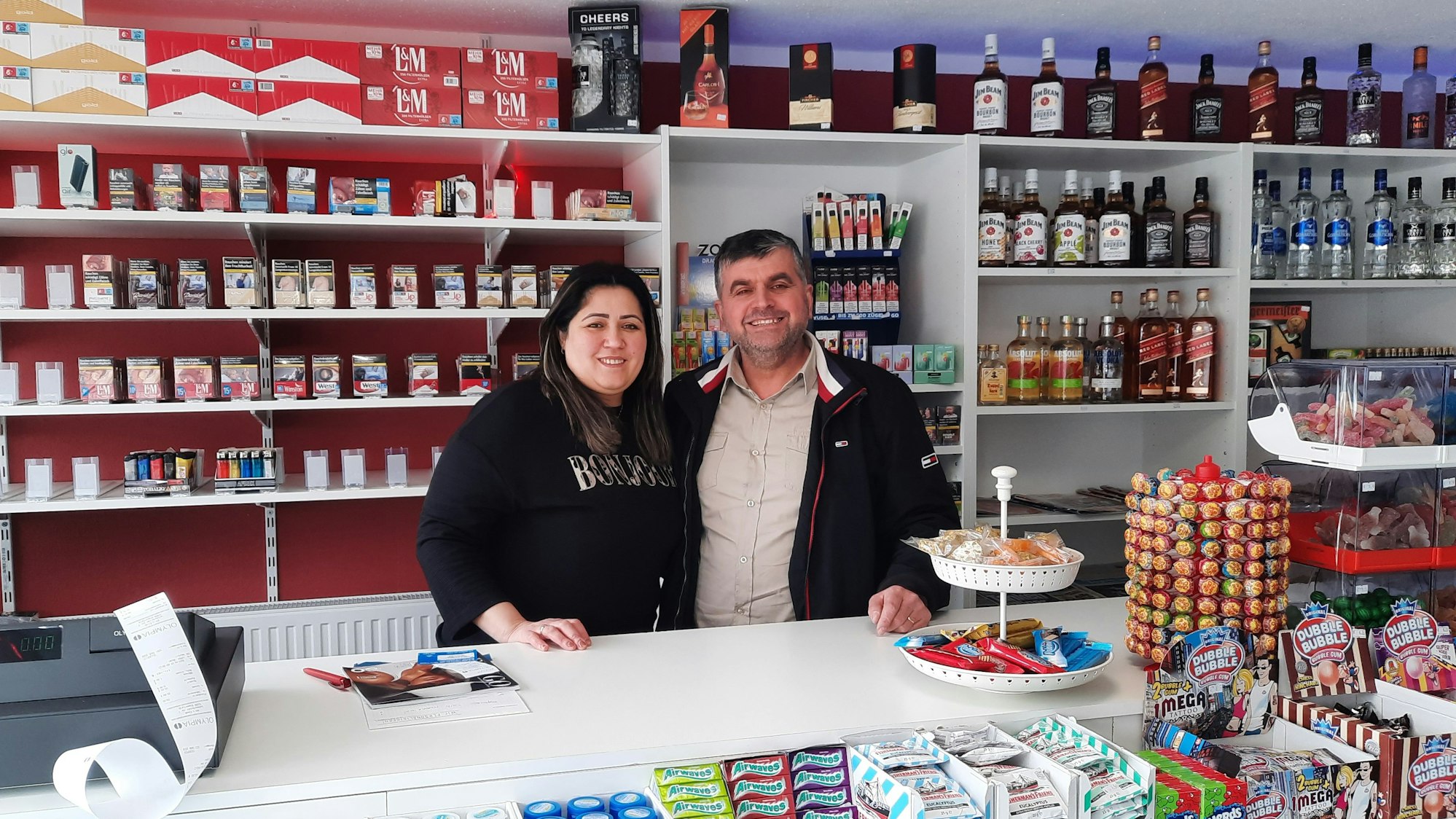 Ein Mann und eine Frau stehen hinter der Ladentheke eines Kiosks.