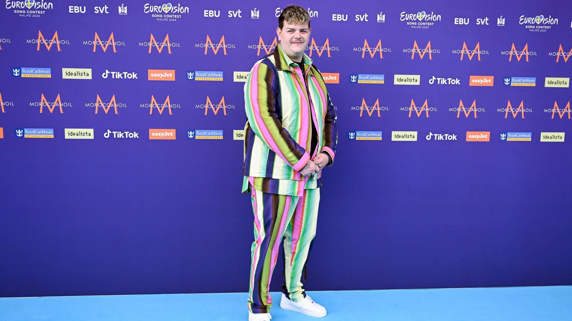 Isaak, der Deutschland repräsentiert, steht auf dem türkisfarbenen Teppich vor der Eröffnungszeremonie des 68. ESC in einem bunt gestreiften Outfit.
