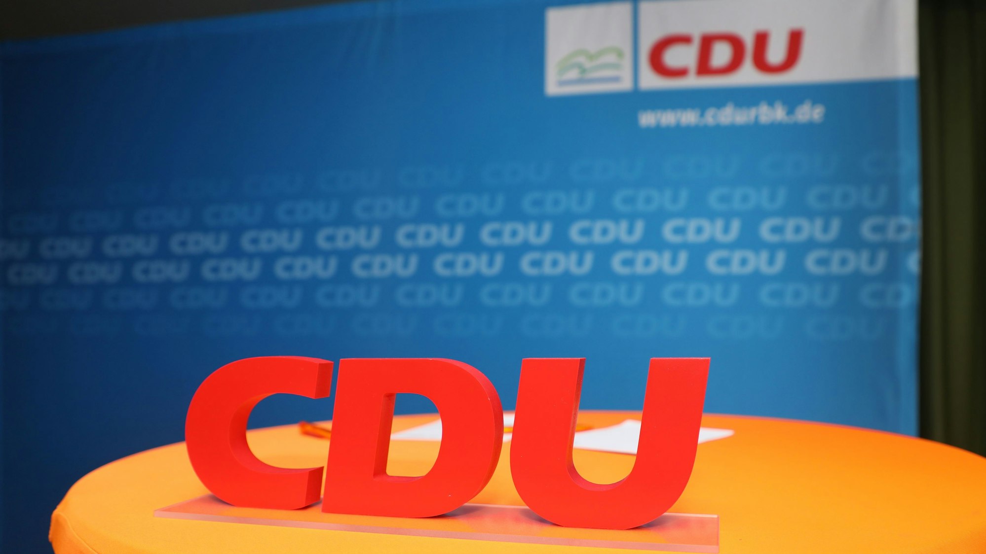 Ein CDU-Schriftzug steht vor eine Parteiwand.