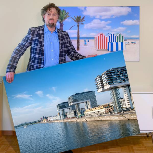 Mann im karierten Jackett hält ein großes Foto von den Kranhäusern in der Hand.