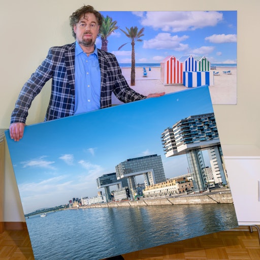 Mann im karierten Jackett hält ein großes Foto von den Kranhäusern in der Hand.