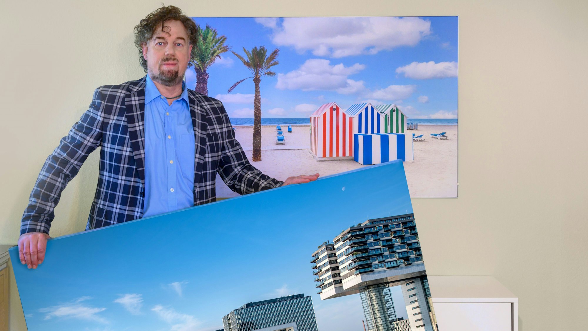 Mann im karierten Jackett hält ein großes Foto von den Kranhäusern in der Hand.