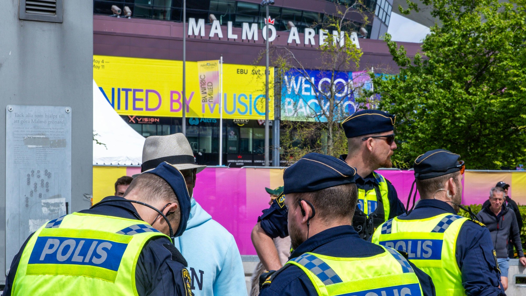 Schwedische Polizisten in grünen Warnwesten kontrollieren Leute vor dem Eingang der Malmö Arena zum Eurovision Song Contest (ESC) 2024.