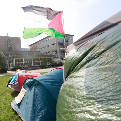 Eine palästinensische Fahne weht auf dem Protestcamp an der Uni Köln. Im Hintergrund ist das Hauptgebäude zu sehen.