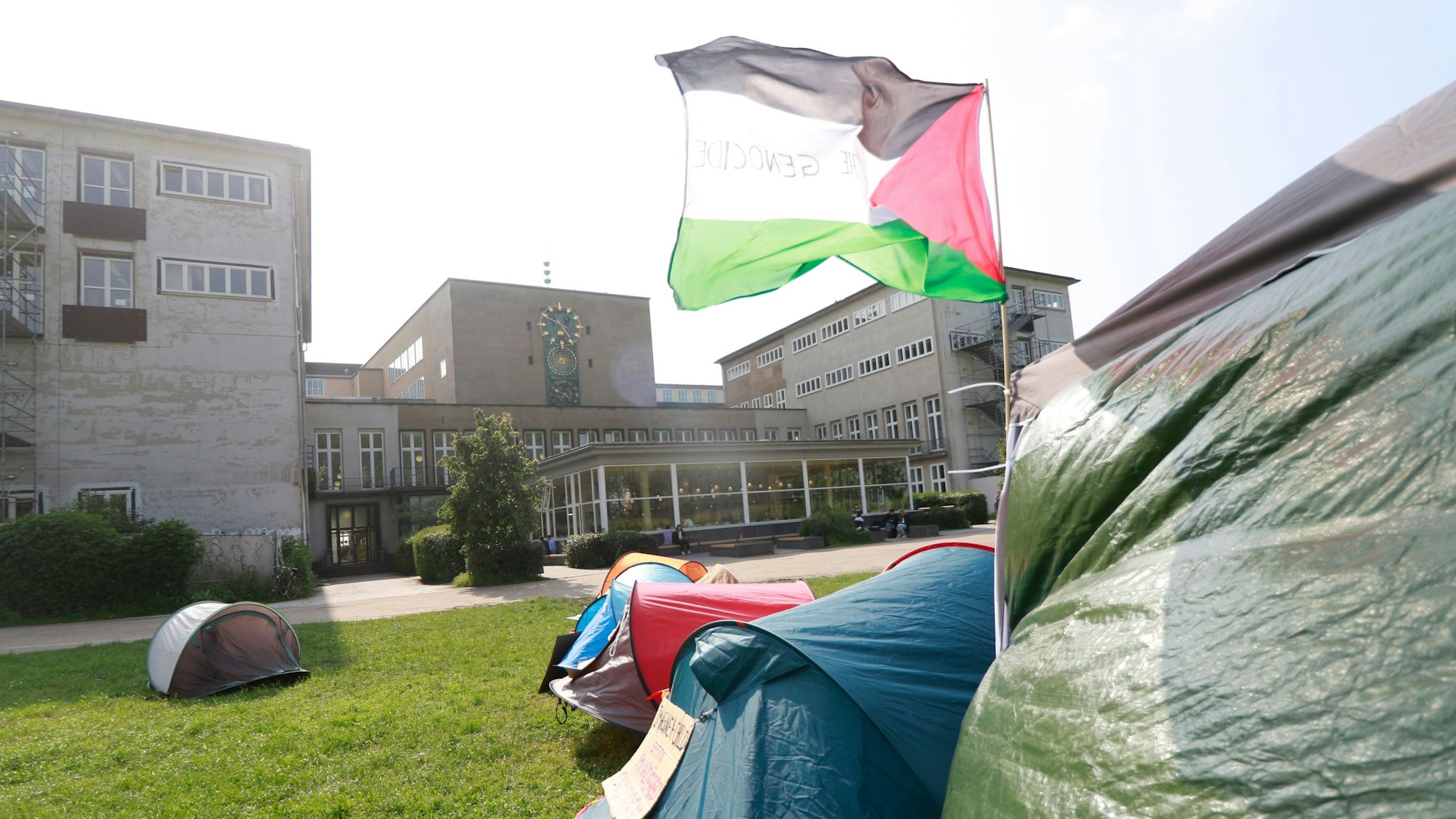 Eine palästinensische Fahne weht auf dem Protestcamp an der Uni Köln. Im Hintergrund ist das Hauptgebäude zu sehen.