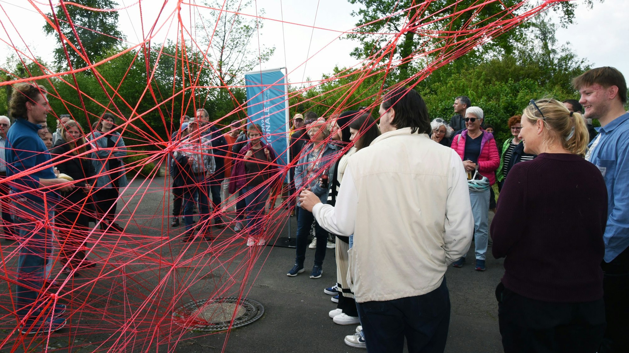 Blick auf ein netz aus roter Schnur, vor dem Menschen stehen.