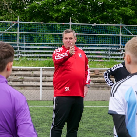 Ein Trainer steht auf einem Fußballplatz und trainiert Fußballspieler.