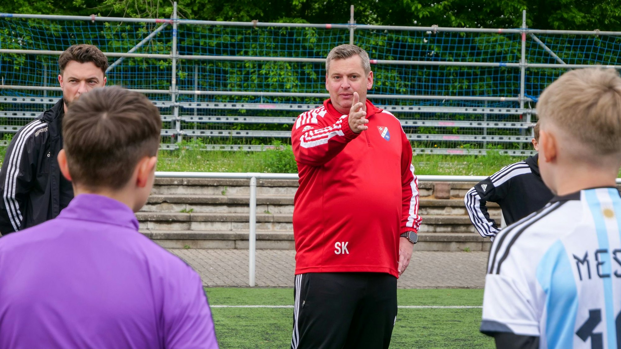 Ein Trainer steht auf einem Fußballplatz und trainiert Fußballspieler.