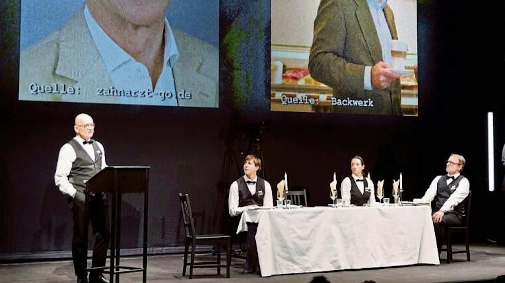 Schauspieler des Berliner Ensembles tragen auf der Bühne Kellner-Kleidung und präsentieren Bilder der Teilnehmer an der geheimen Rechtsextremen-Konferenz in Potsdam