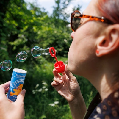 ILLUSTRATION - 24.05.2023, Baden-Württemberg, Stuttgart: Eine Frau bläst Seifenblasen mit einem Spielzeug der Marke Pustefix. Pustefix feiert in diesem Jahr sein 75-jähriges Bestehen. Mit Seifenblasen-Spielen made in Germany wurde die Firma berühmt. Der Markt ist in der Branche aber hart umkämpft. Foto: Julian Rettig/dpa +++ dpa-Bildfunk +++