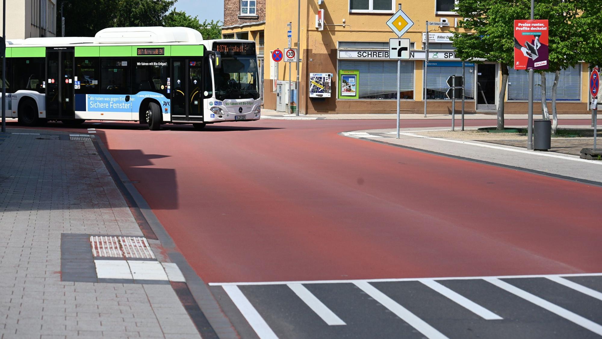 Auf dem Foto ist die Carl-Schurz-Straße in Erftstadt-Liblar zu sehen. Ein Bus fährt um die Ecke. Die gesamte Kreuzung ist mit einem roten Belag versehen.