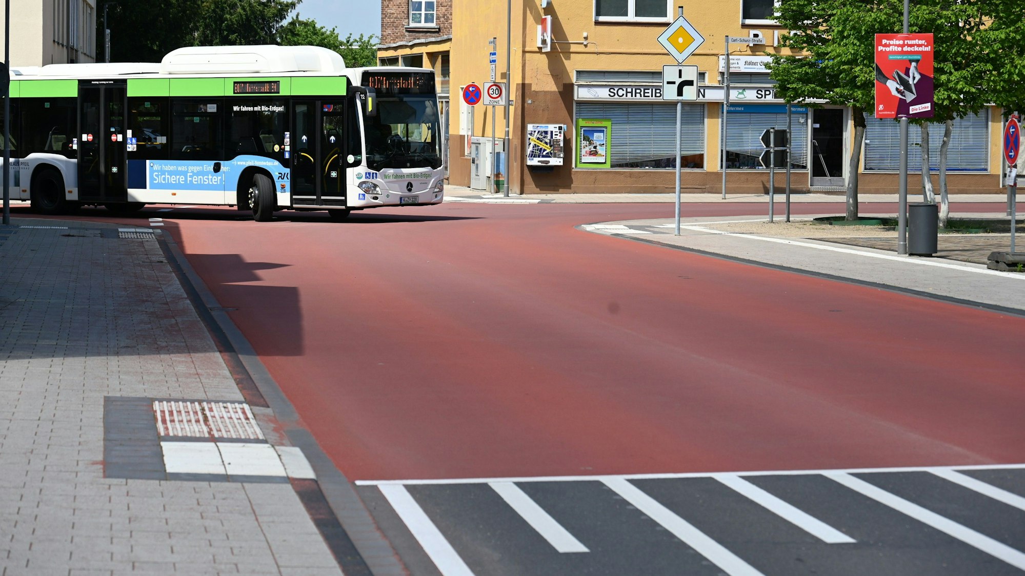 Auf dem Foto ist die Carl-Schurz-Straße in Erftstadt-Liblar zu sehen. Ein Bus fährt um die Ecke. Die gesamte Kreuzung ist mit einem roten Belag versehen.