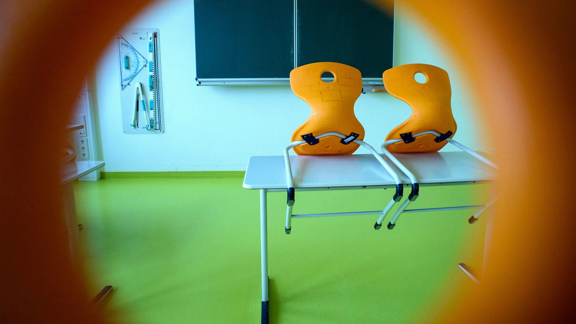 Stühle stehen in einem leeren Klassenzimmer auf einem Tisch. In Würselen bei Aachen hatte die Kleiderwahl eines Lehrers nun Konsequenzen. (Symbolbild)