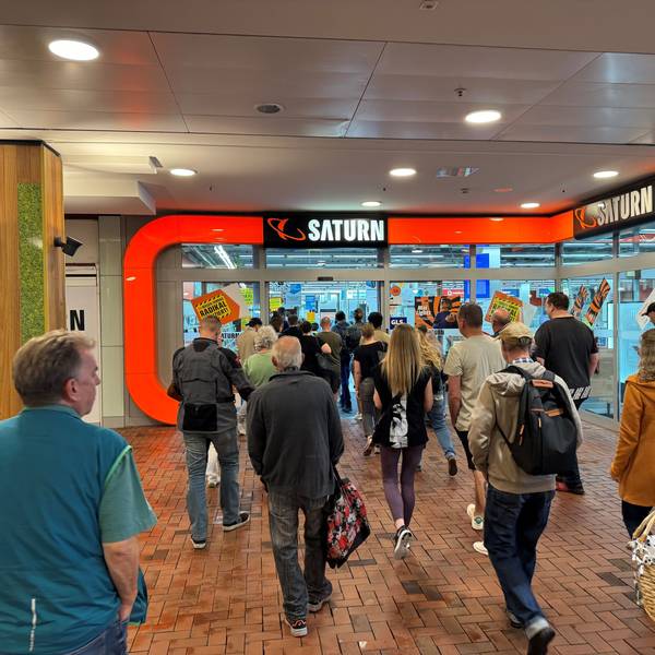 Eine Gruppe von Menschen vor dem Eingang des Saturn-Markts im Einkaufszentrum Hürth-Park.