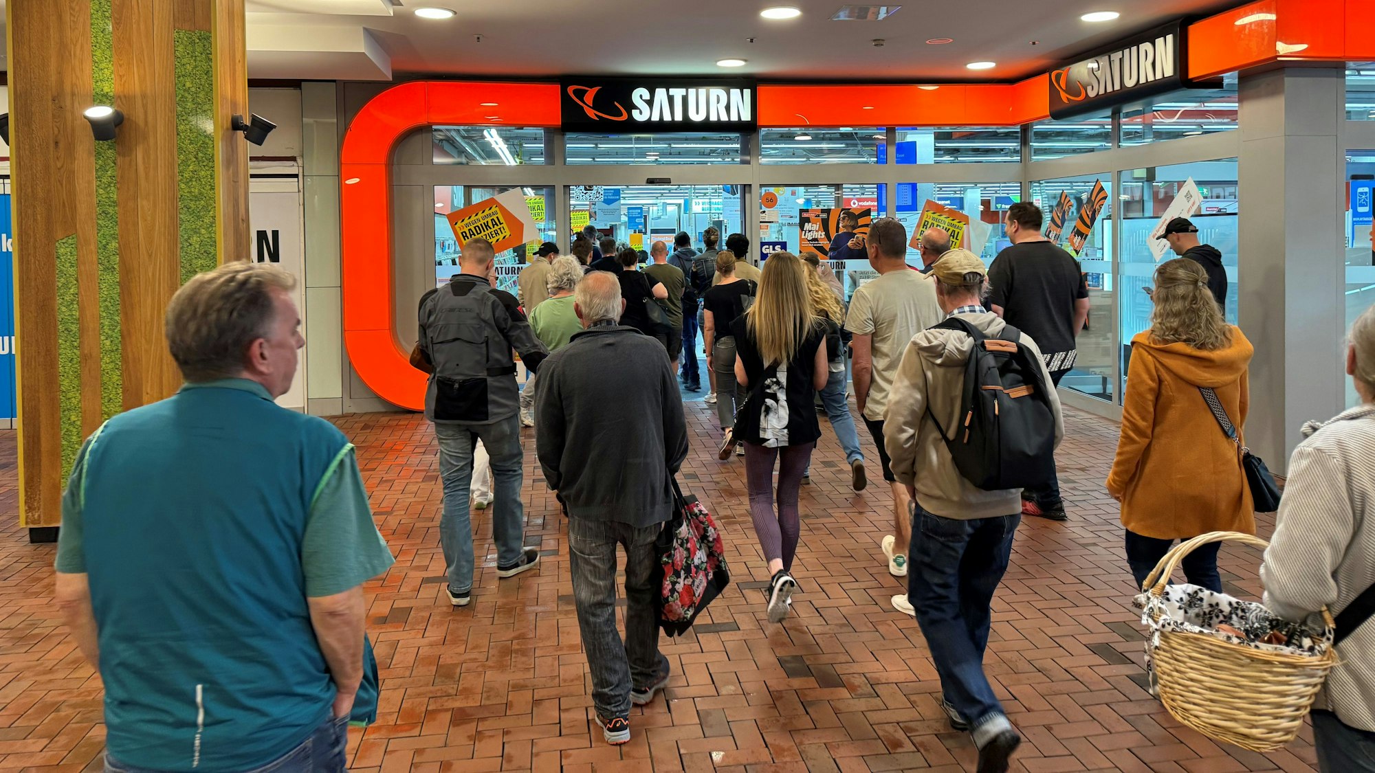 Eine Gruppe von Menschen vor dem Eingang des Saturn-Markts im Einkaufszentrum Hürth-Park.