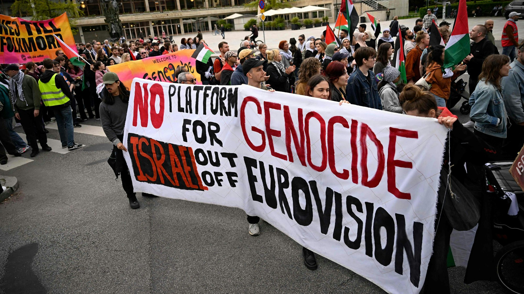 Eine Gruppe von Pro-palästinensische Demonstranten haben sich auf einem Platz versammelt und halten ein Transparent hoch, auf dem steht, dass sie Israel nicht beim ESC sehen wollen