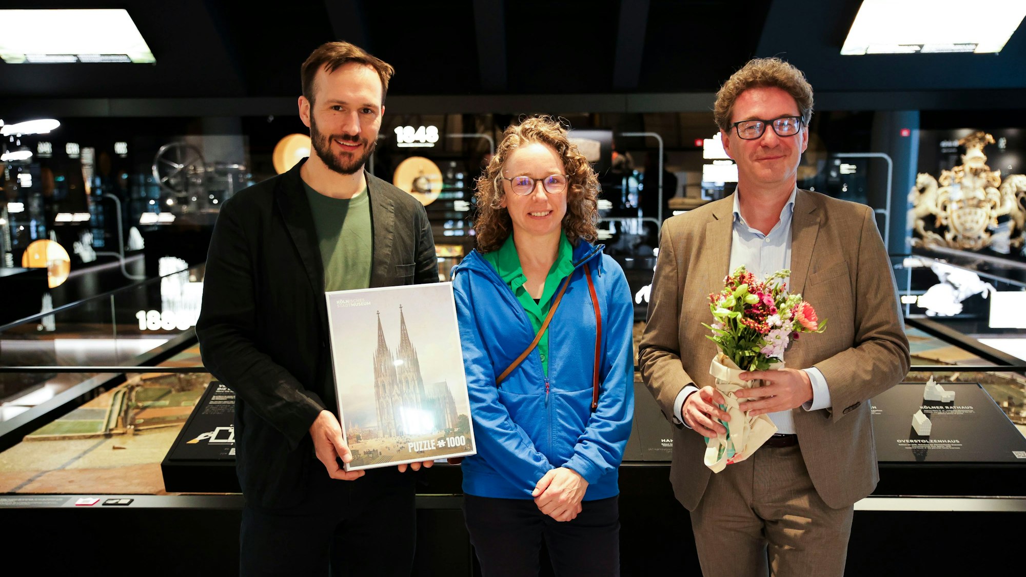 Kurator Sascha Pries (l.) und Direktor Matthias Hamann begrüßen die 15.000ste Besucherin des Kölner Stadtmuseums.