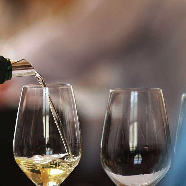 Aus einem verdeckten Bocksbeutel wird bei einem Wein-Wettbewerb ein Glas mit Weißwein gefüllt.