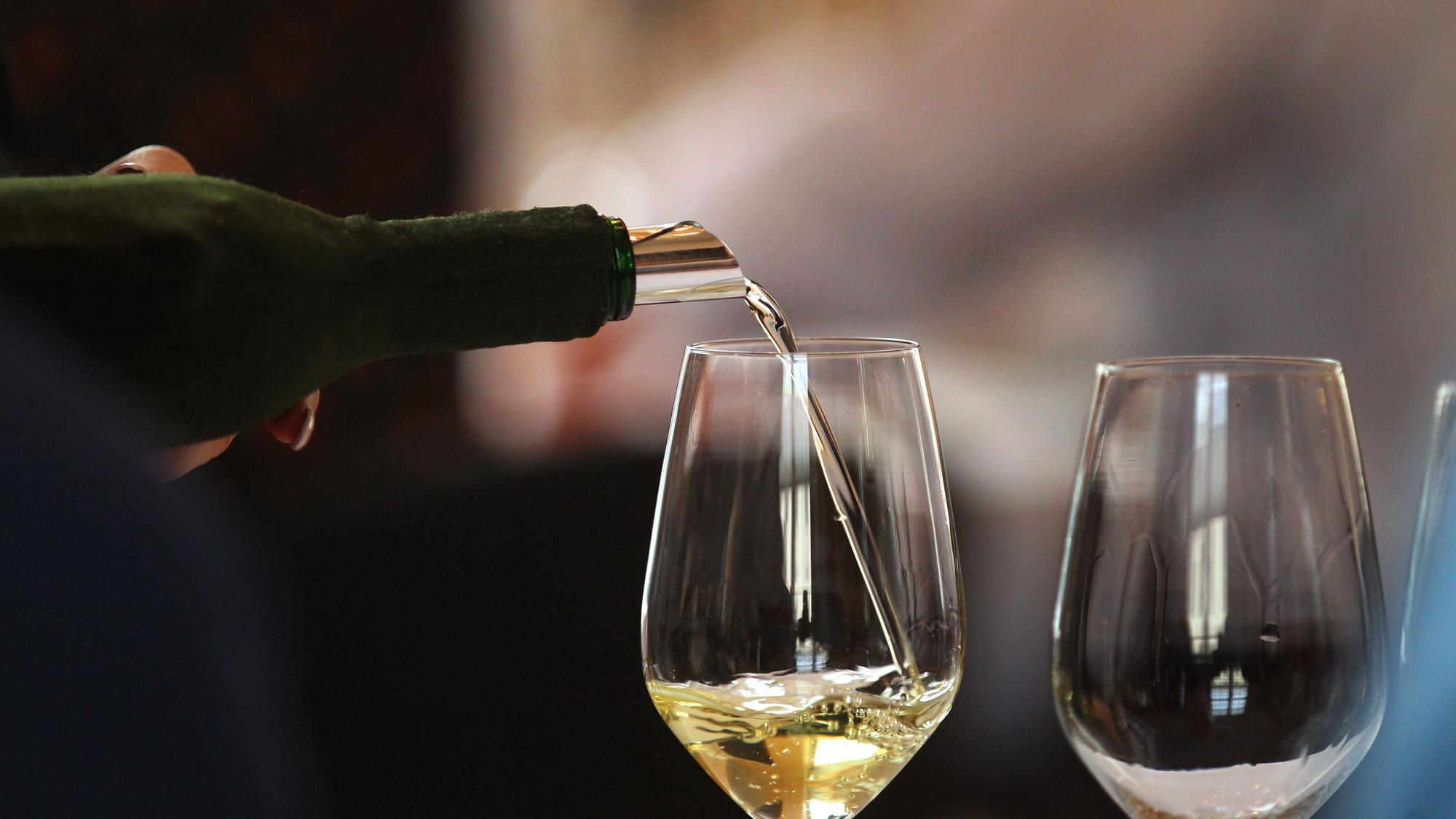 Aus einem verdeckten Bocksbeutel wird ein Glas mit Weißwein gefüllt. (Symbolbild)