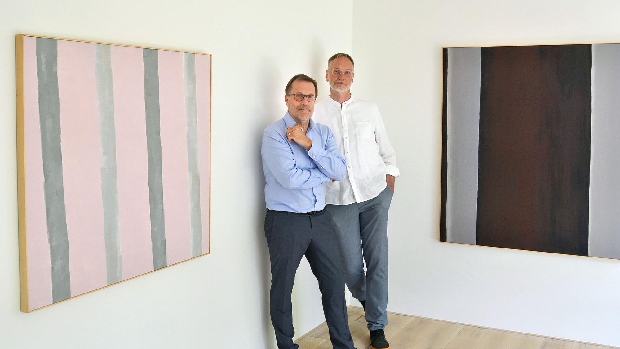 Die Galeristen Helmut Doll und Frank Gunzelmann stehen an zwei Werken, die sie in der aktuellen Ausstellung in Schweinheim zeigen.