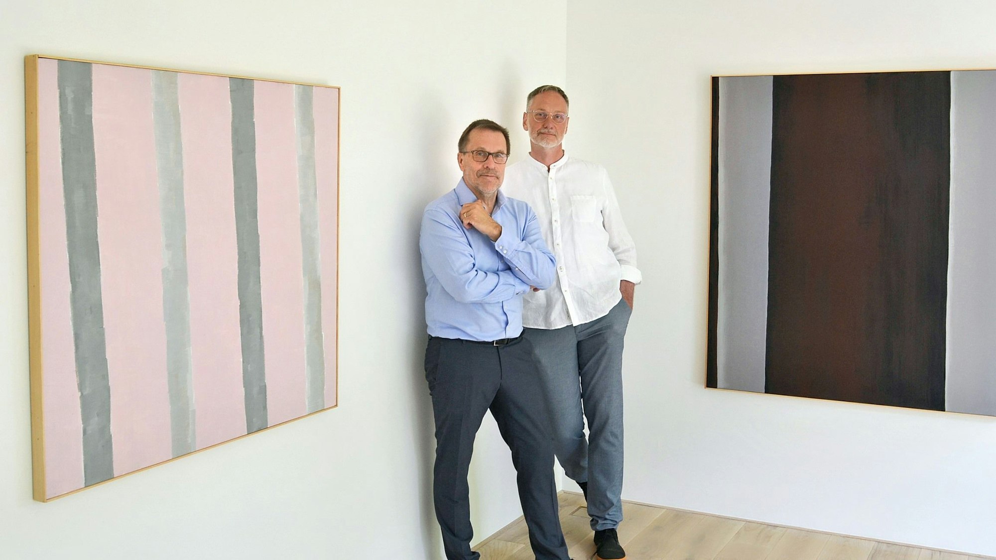 Die Galeristen Helmut Doll und Frank Gunzelmann stehen an zwei Werken, die sie in der aktuellen Ausstellung in Schweinheim zeigen.