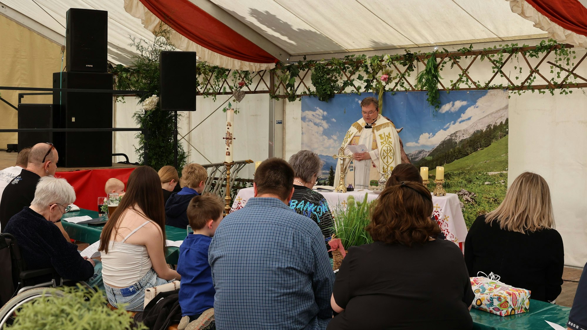 Blick in das Festzelt, in dem die Taufe stattfand. Die Gläubigen sitzen vor dem Altar, an dem der Pfarrer steht.
