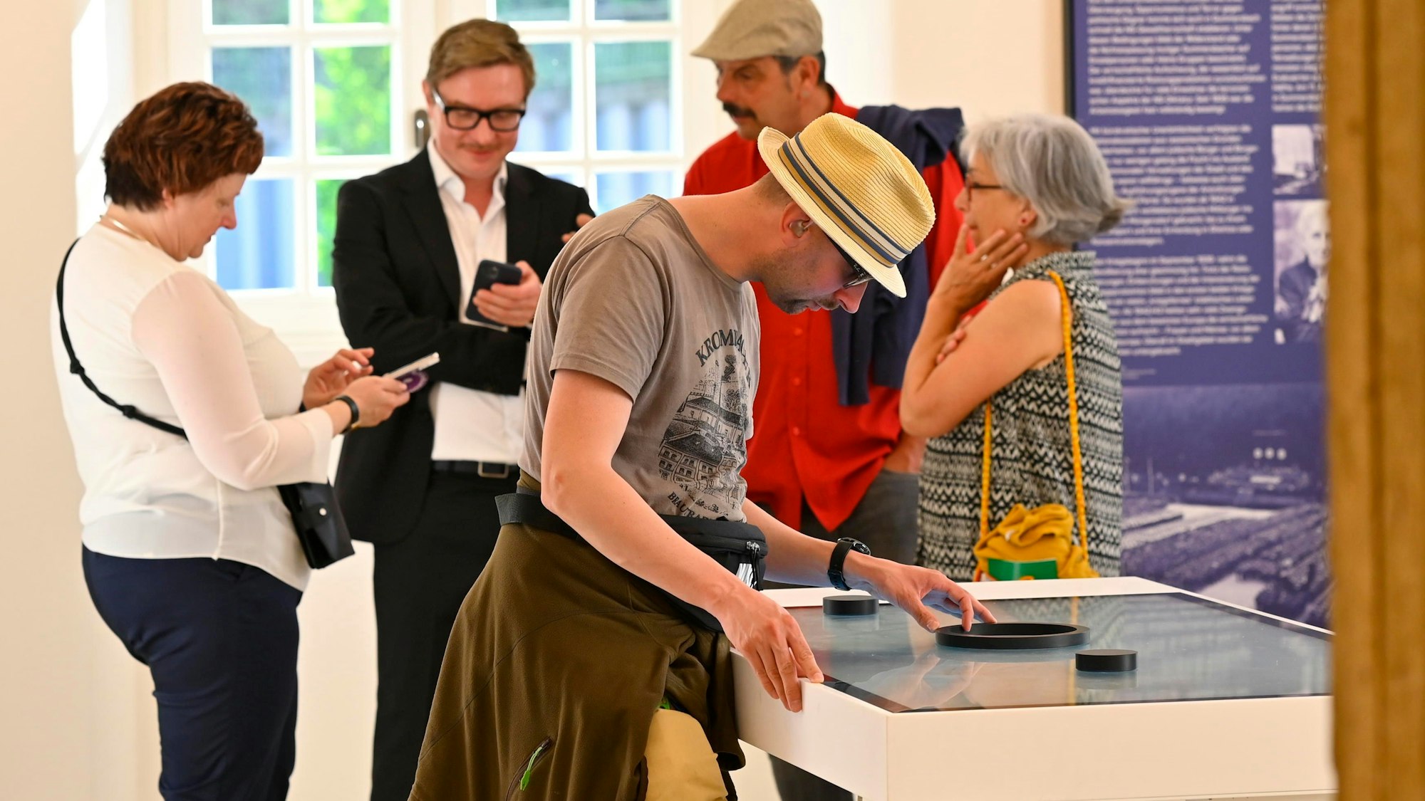 Zu sehen sind Menschen, die sich in einem Ausstellungsraum informieren.