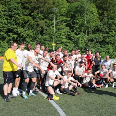 Fußballchef Jürgen Liehn überreicht die Schale an Kapitän Severin Brochhaus. Im Hintergrund jubelt die Mannschaft.