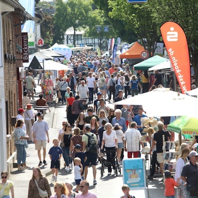Viele Menschen gehen auf einer für Autos gesperrten Straße an Info-Ständen vorbei.