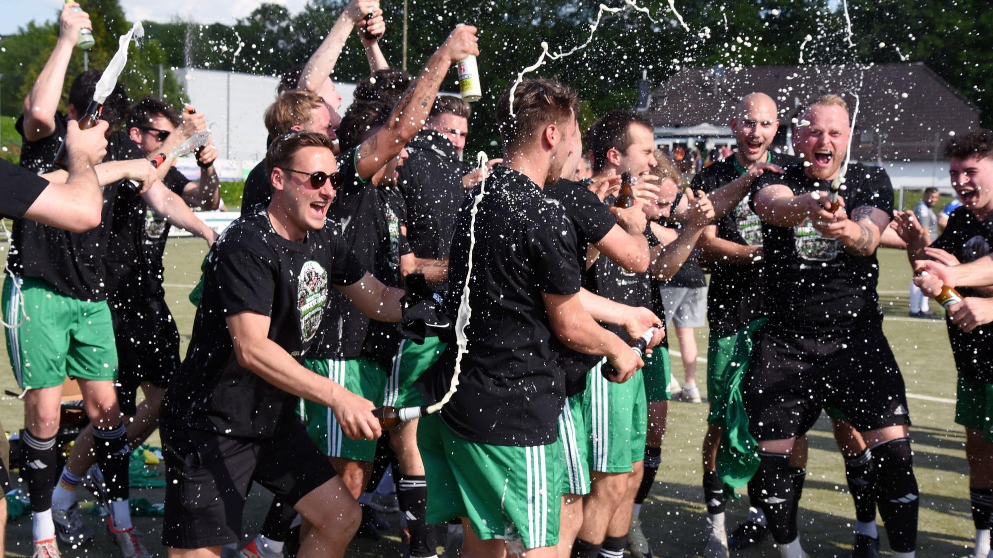 Laut schreiend laufen die Lindlarer Spieler über das Feld und begießen sich mit Sekt.