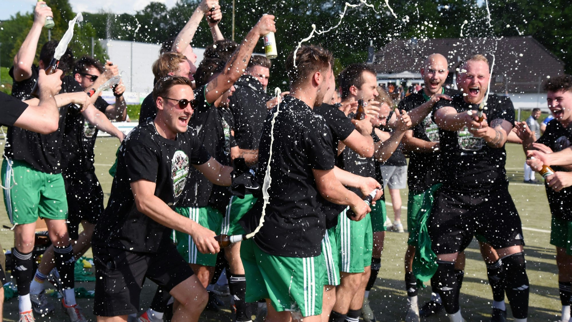 Laut schreiend laufen die Lindlarer Spieler über das Feld und begießen sich mit Sekt.