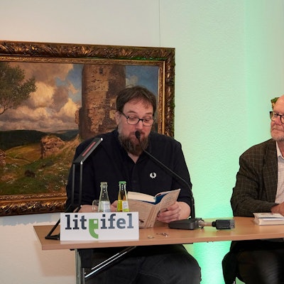 Carsten Sebastian Henn und Ralf Kramp sitzen nebeneinander bei einer Lesung im Rahmen der Lit.Eifel im Eifelmuseum in Blankenheim.