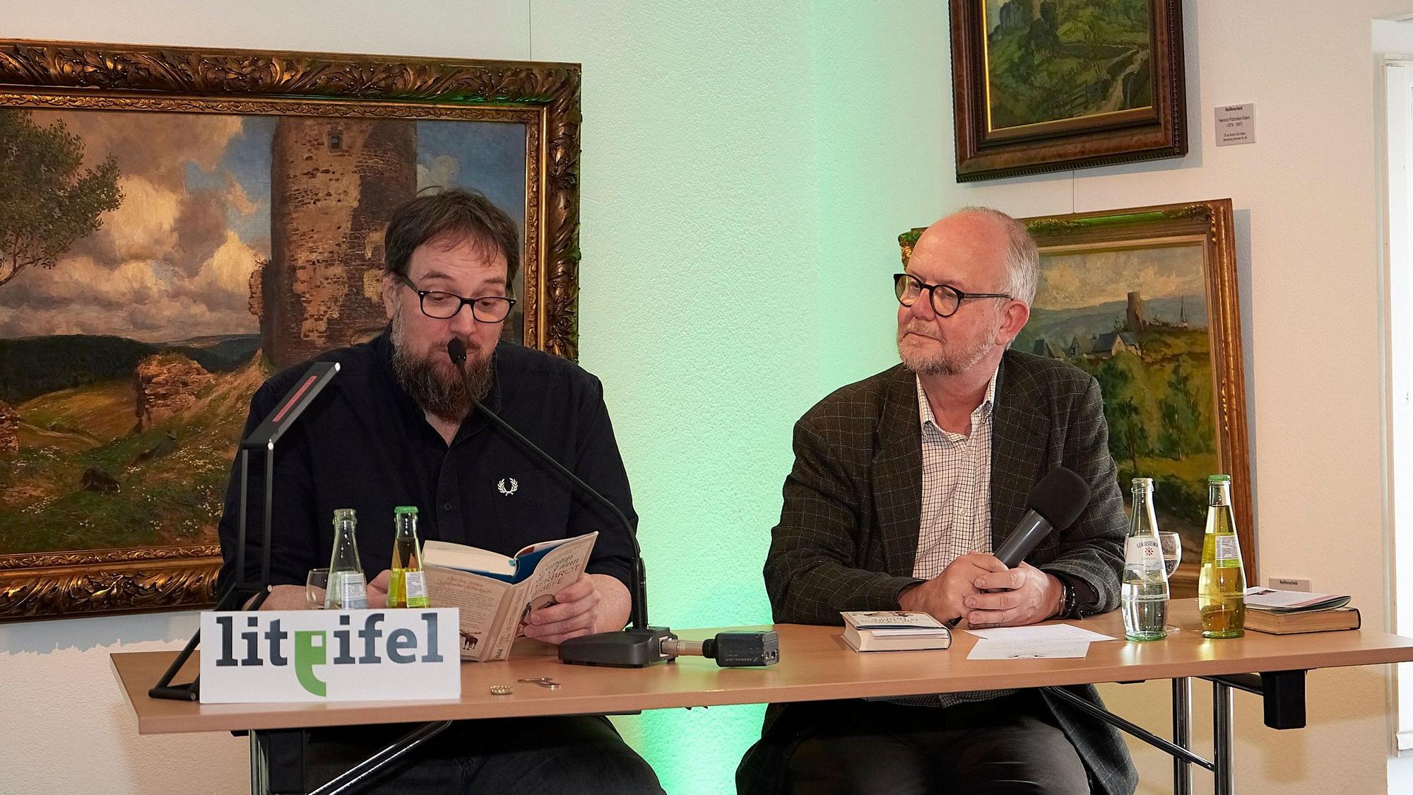 Carsten Sebastian Henn und Ralf Kramp sitzen nebeneinander bei einer Lesung im Rahmen der Lit.Eifel im Eifelmuseum in Blankenheim.