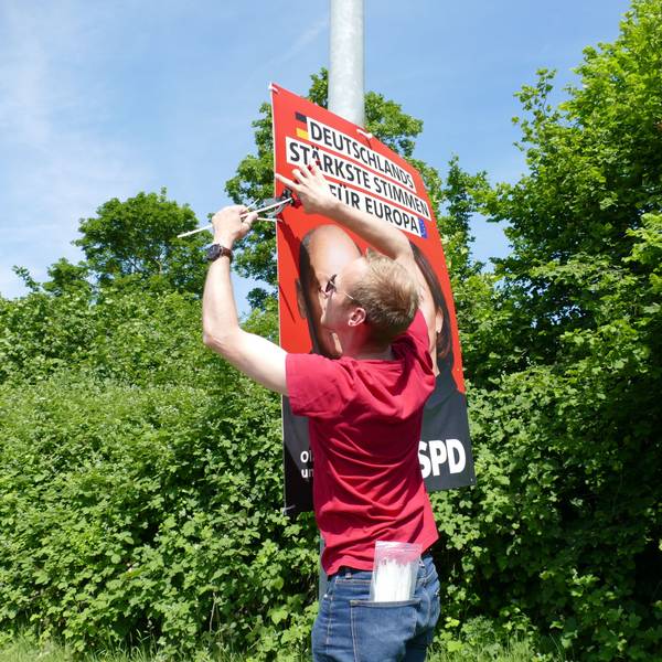 Michael Richter, der Kreisgeschäftsführer der SPD in Bonn und dem Rhein-Sieg-Kreis, hängt an einem Laternenmast ein Plakat zur Europawahl auf.