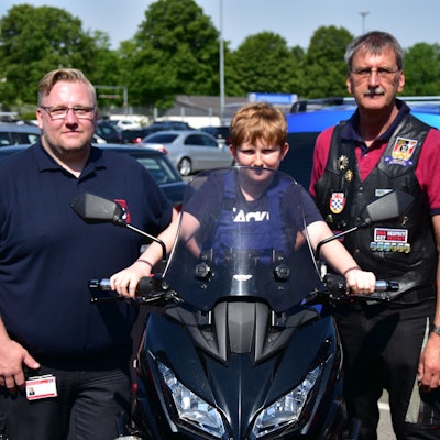 Nachwuchs-Feuerwehrmann Finn sitzt bei der Spendenaktion der Biker der Bundespolizei auf einem Motorrad, eingerahmt von den beiden Bikern Markus Mattern (l.) und Dirk Stenzel (r.).