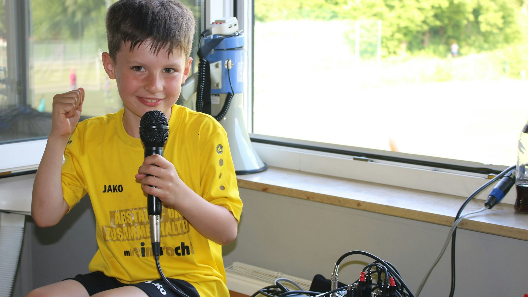 Der siebenjährige Bela Rintjes hält das Mikrofon in der Hand und lachte in die Kamera.