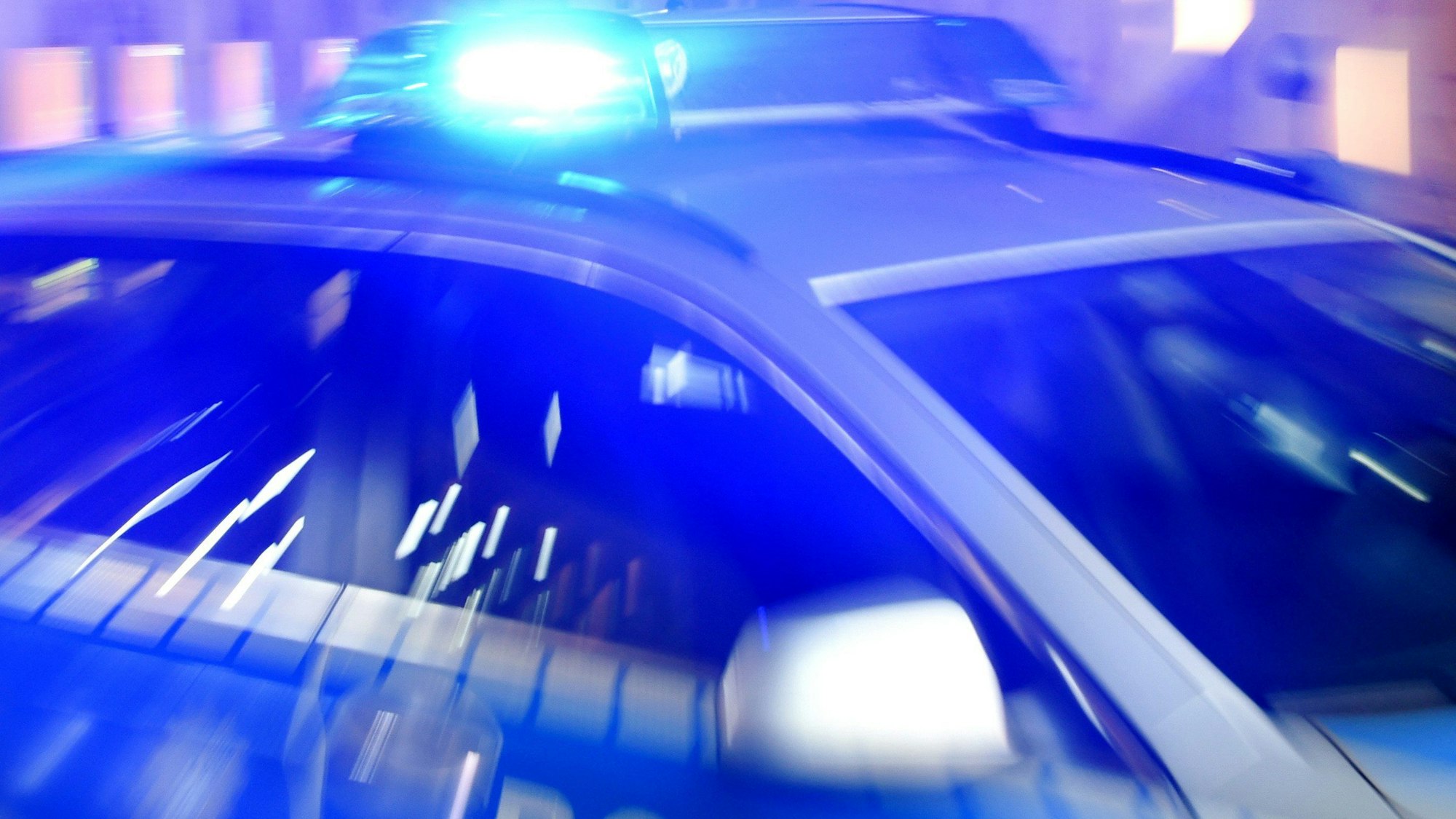 Ein Streifenwagen der Polizei steht mit eingeschaltetem Blaulicht auf der Straße.