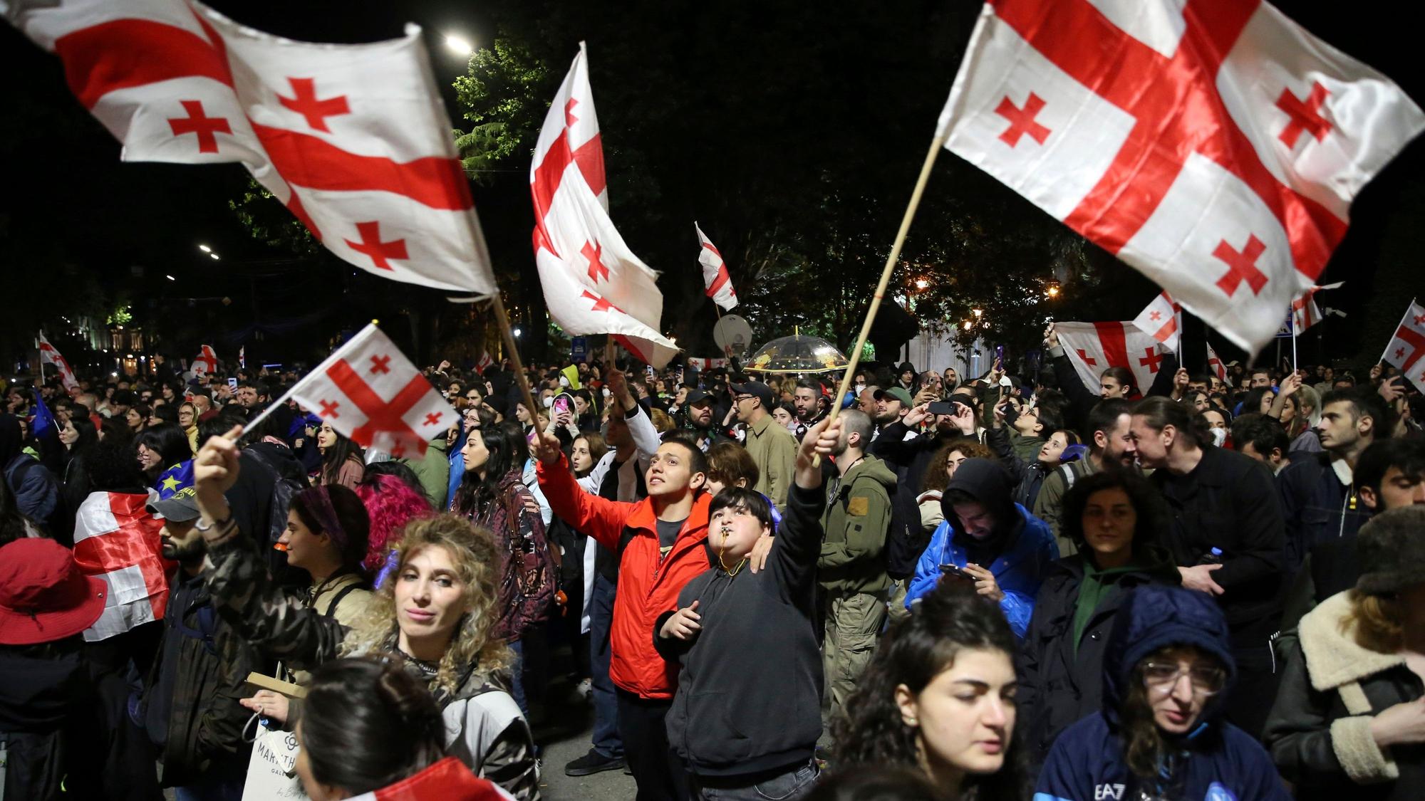 13.05.2024, Georgien, Tiflis: Demonstranten mit georgischen Fahnen nehmen vor dem Parlamentsgebäude an einer Demonstration gegen ein Gesetz teil, das den ausländischen Einfluss auf die Zivilgesellschaft beschneiden soll.