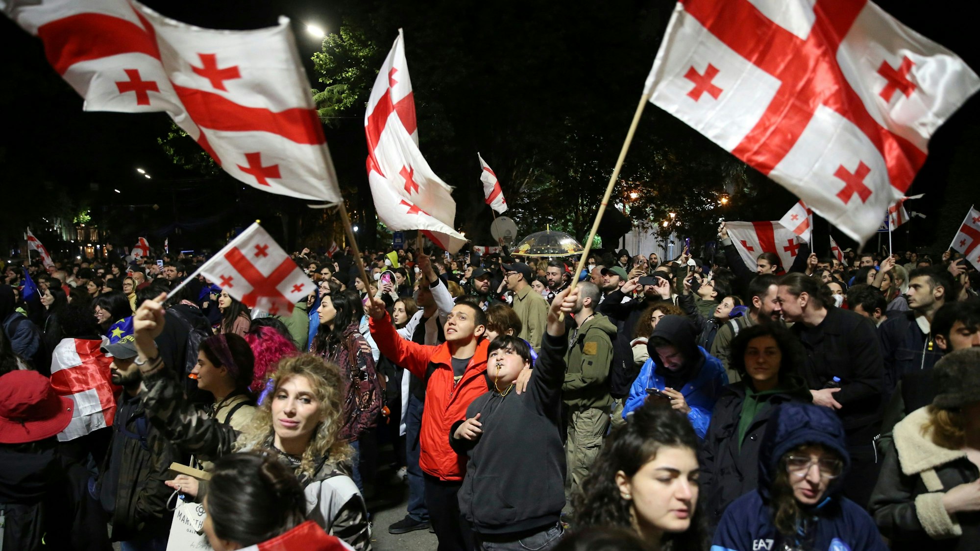 13.05.2024, Georgien, Tiflis: Demonstranten mit georgischen Fahnen nehmen vor dem Parlamentsgebäude an einer Demonstration gegen ein Gesetz teil, das den ausländischen Einfluss auf die Zivilgesellschaft beschneiden soll.