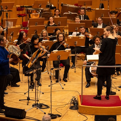 Das WDR-Sinfonieorchester spielt, im Fokus des Bildes sind die Dirigentin sowie die Streicher und Bläser zu sehen.