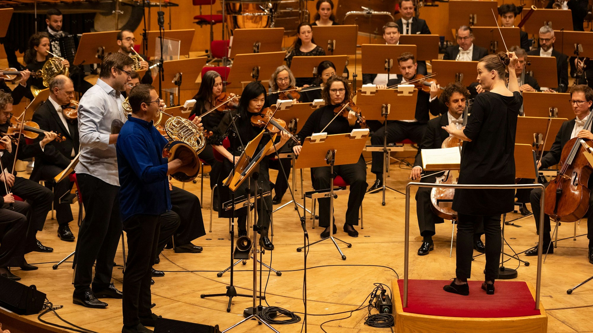 Das WDR-Sinfonieorchester spielt, im Fokus des Bildes sind die Dirigentin sowie die Streicher und Bläser zu sehen.