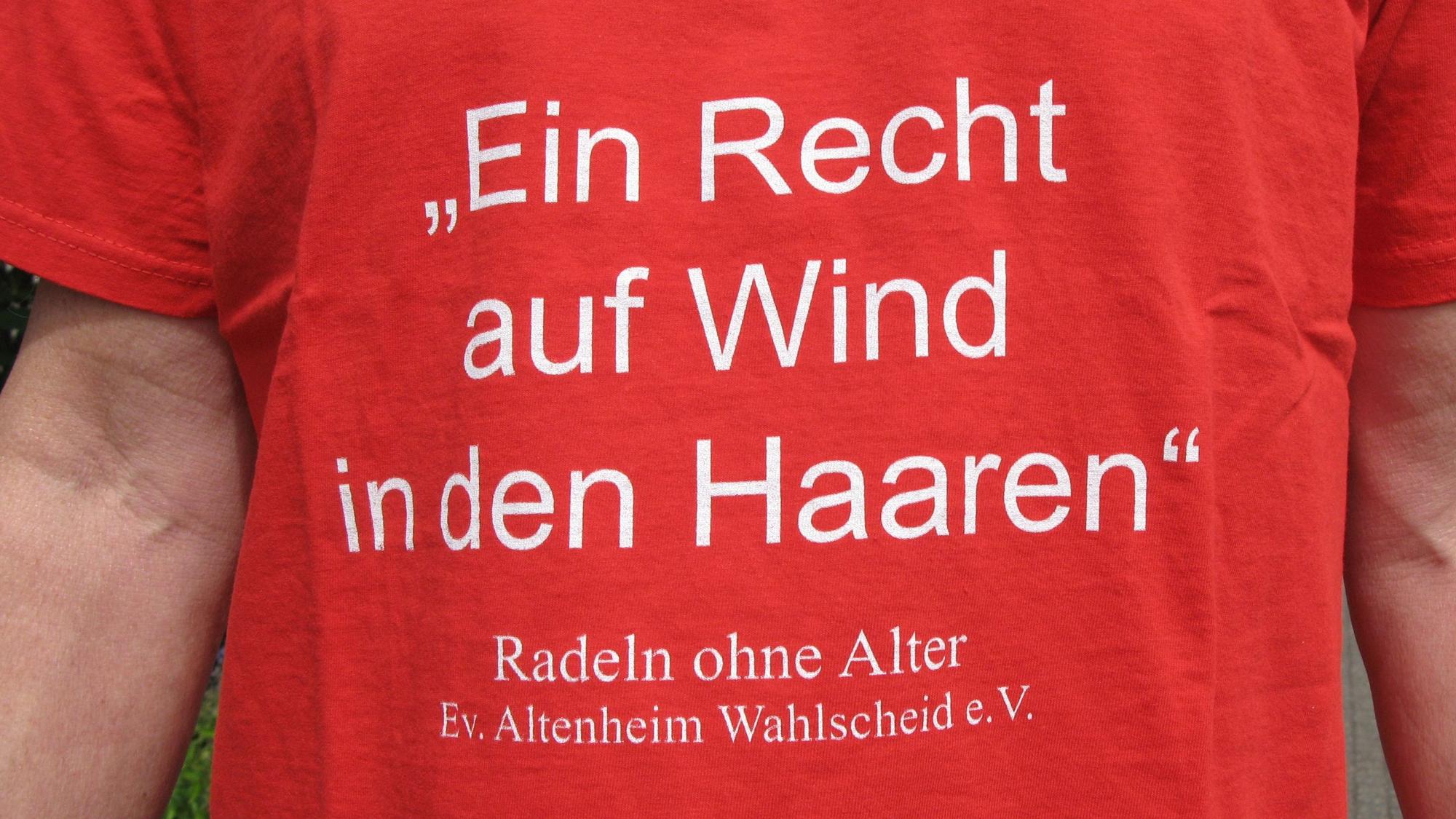 Auf einem roten T-Shirt steht „Ein Recht auf Wind in den Haaren – Radeln ohne Alter, Evangelisches Altenheim Wahlscheid e.V.“