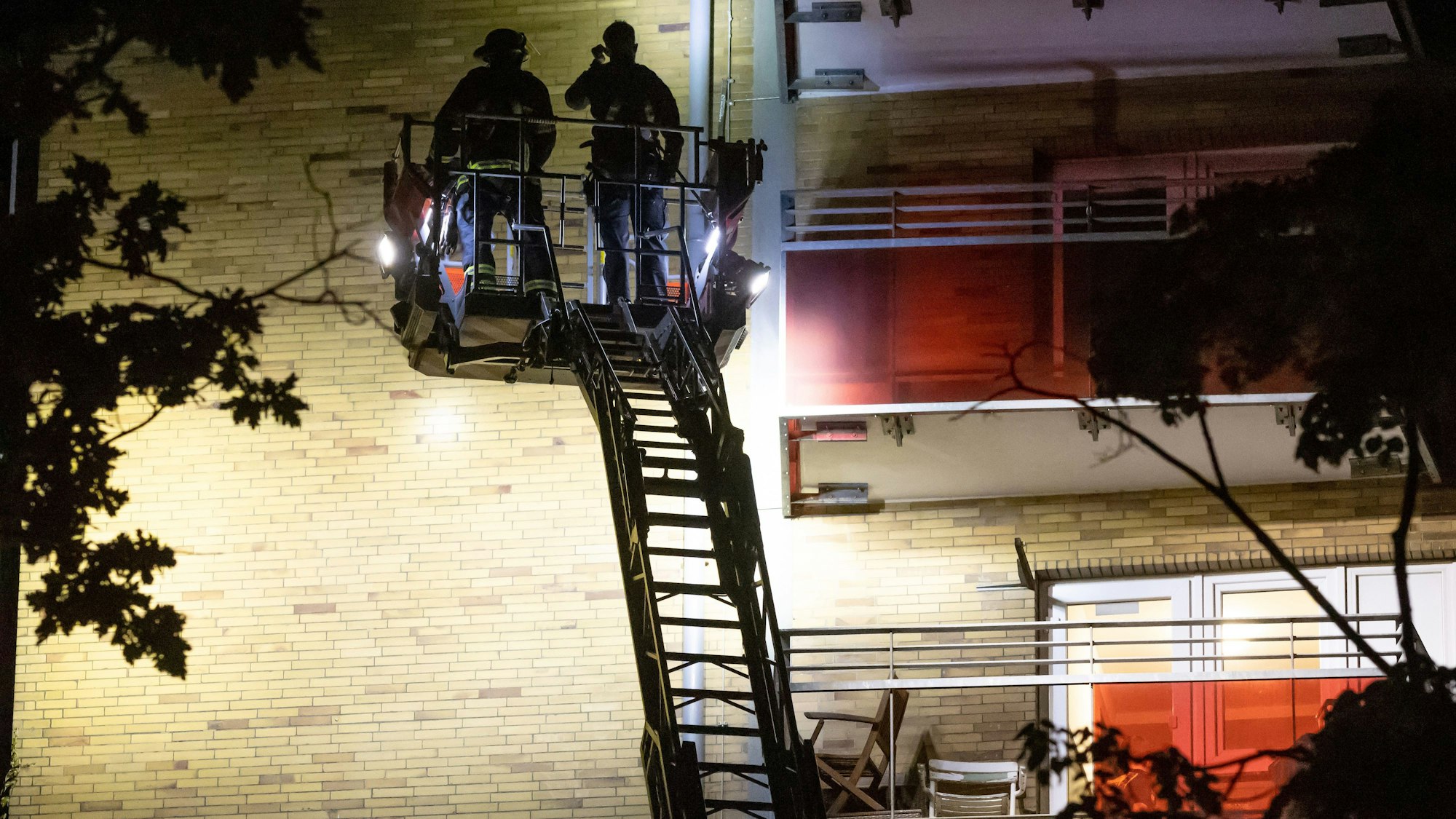 12.05.2024, Hamburg: Einsatzkräfte stehen auf einer Drehleiter an einem Hochhaus im Stadtteil Altona und suchen die Fassade nach Beschädigungen durch Schüsse ab.