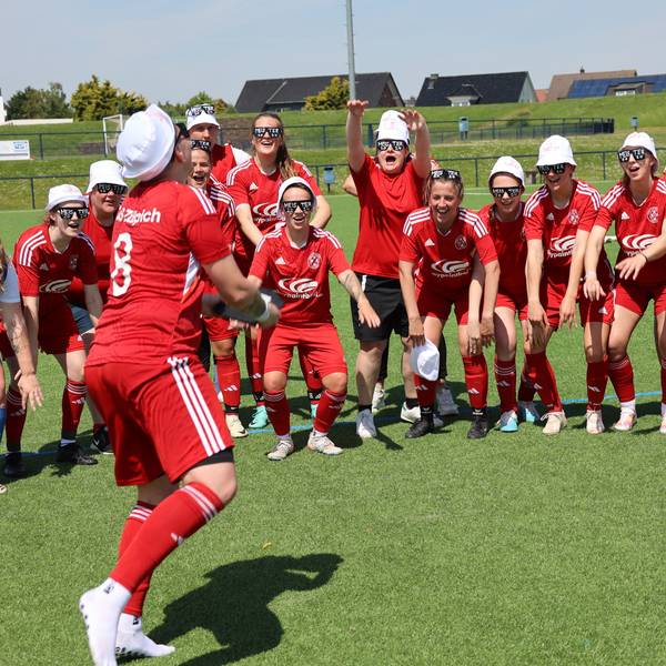 Fußballspielerinnen tragen weiße Kappen und jubeln.