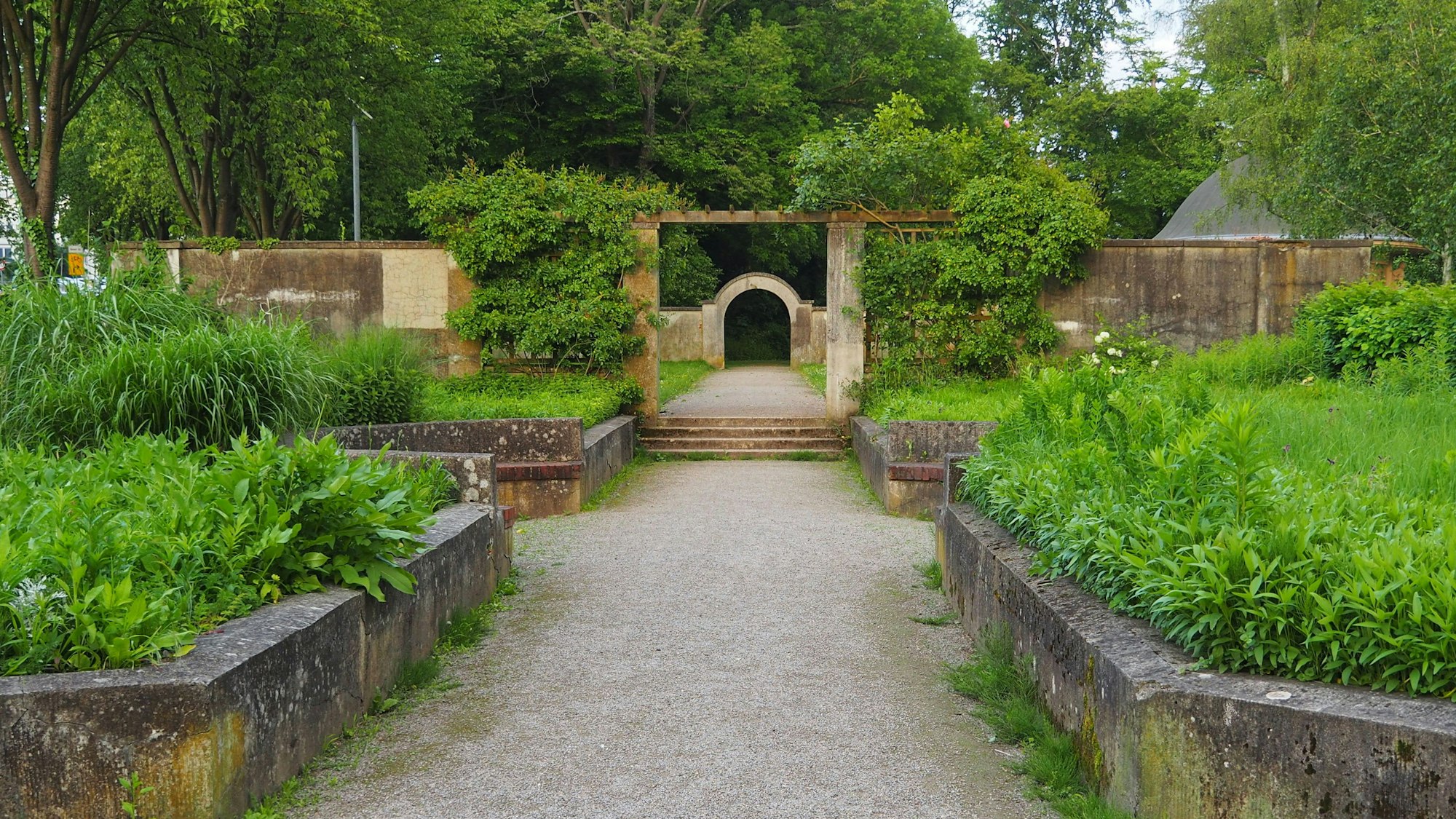 Im Staudengarten mit seinen Sitznischen, Torbögen, Rankgerüsten und Staudenbeeten amtmet der Geist der 1920er Jahre. Das Mauerwerk ist sehr in die Jahre gekommen und soll saniert werden.