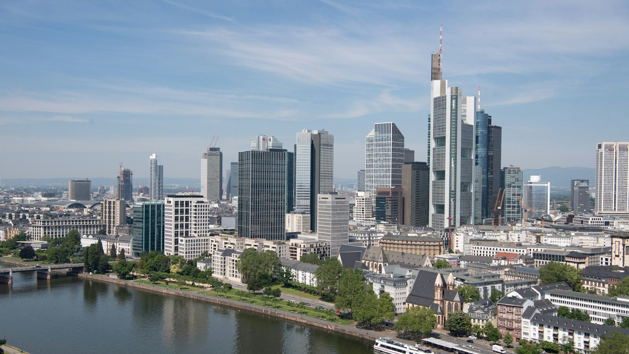 Nur wenige Wolken ziehen über den Himmel über der Bankenskyline von Frankfurt und den Main hinweg.