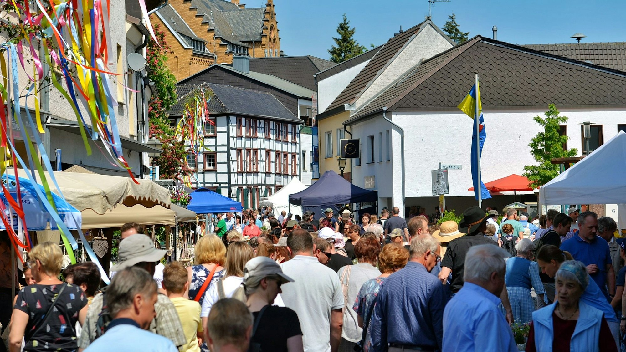 Viele Menschen drängen sich zwischen Marktständen und Fachwerkhäusern.