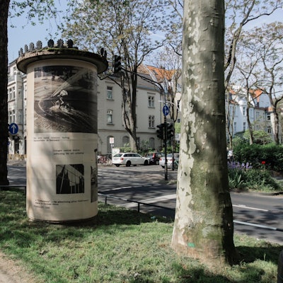 Zu sehen ist eine Litfaßsäule auf einem Grünstreifen.
