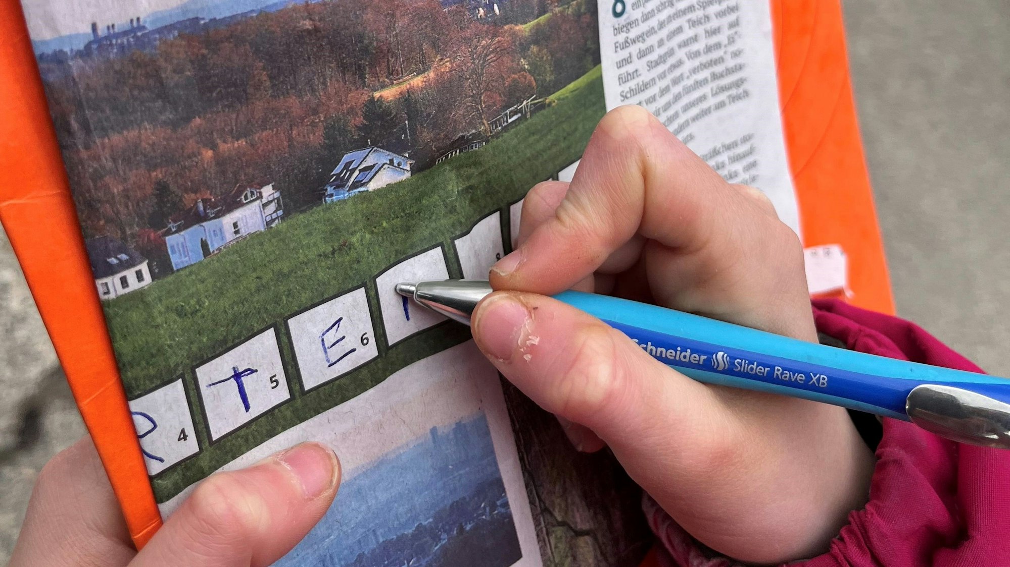 Eine Kinderhand füllt mit einem Kugelschreiber die Rätselkästchen einer Rätseltour der Lokalredaktion Rhein-Berg aus.