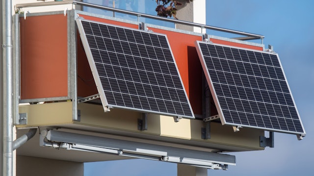 Solarmodule für ein sogenanntes Balkonkraftwerk hängen an einem Balkon.